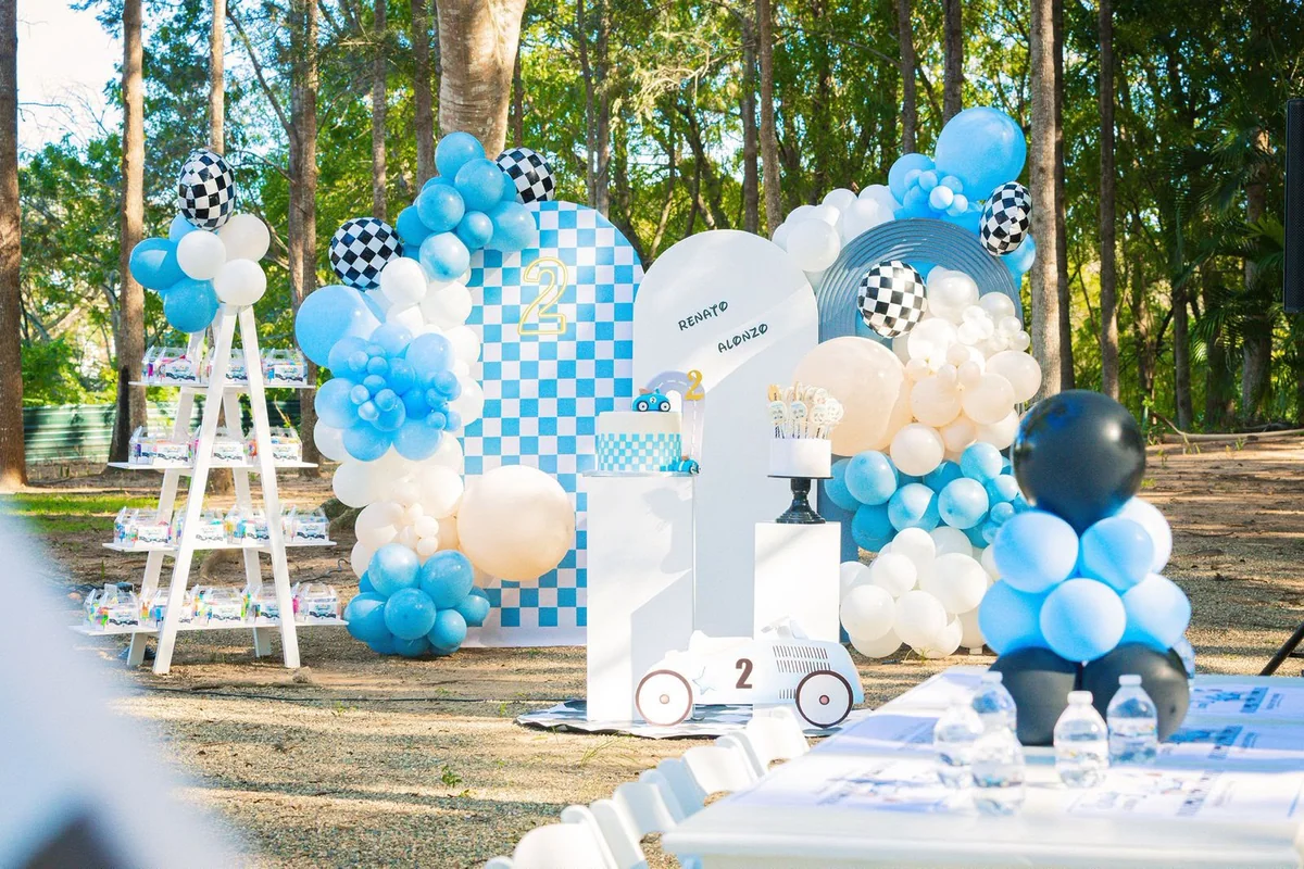 Decoración de cumpleaños al aire libre con globos azules y blancos y temática de carreras