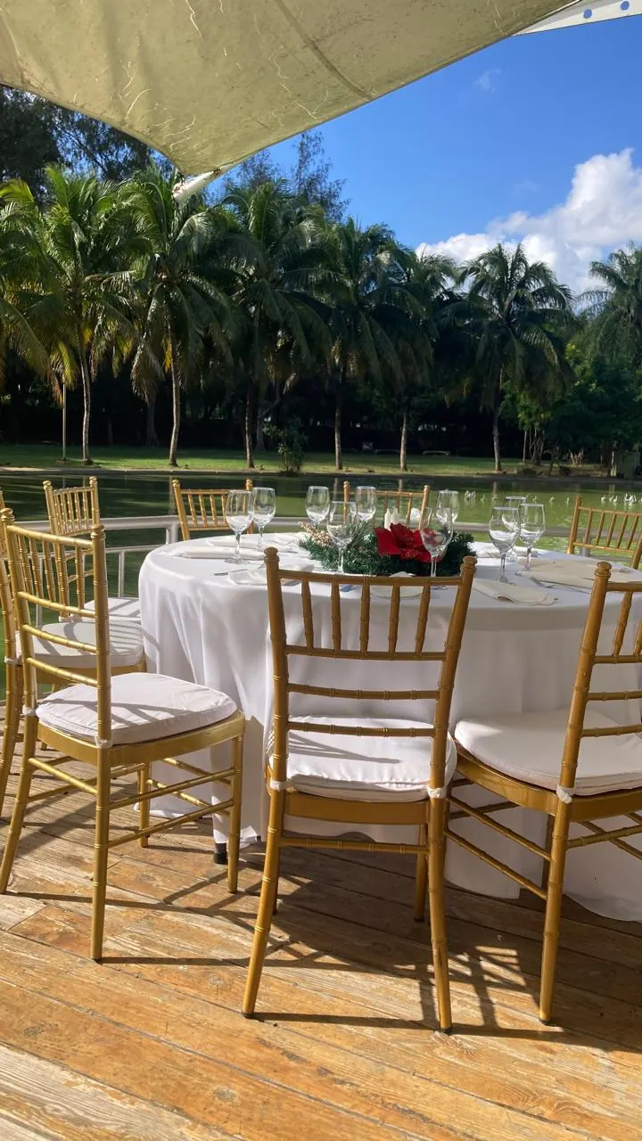 Mesa de evento con mantel blanco y sillas doradas en una terraza al aire libre
